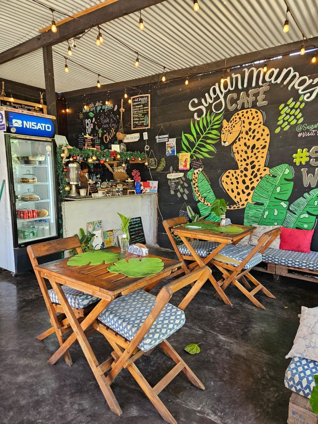 Inside Sugar Mama's Café — tables, fairy lights and our jaguar mural
